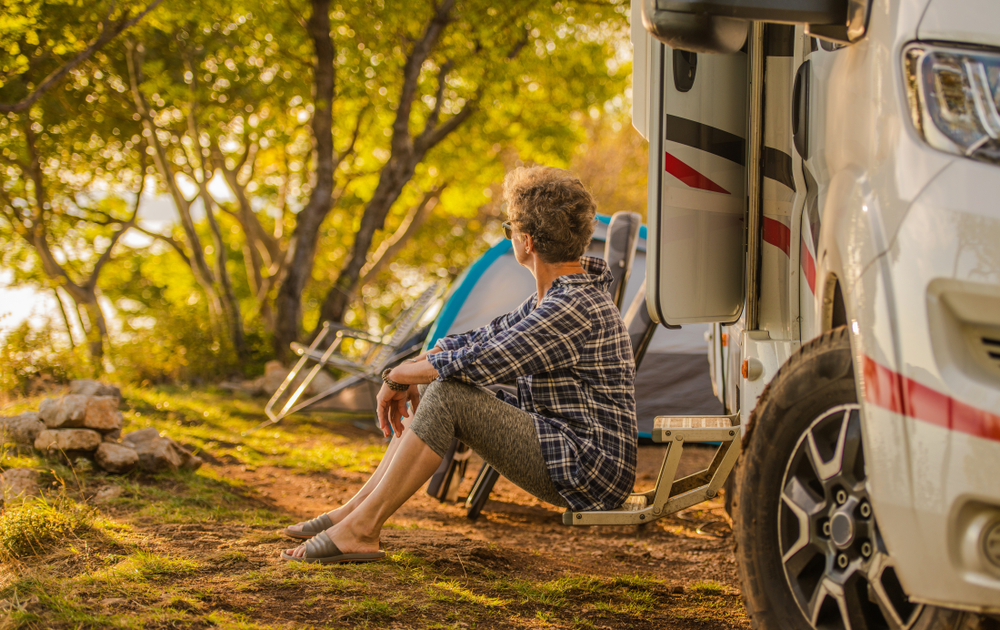 Senior woman sits outside of her RV and admires the scenery.