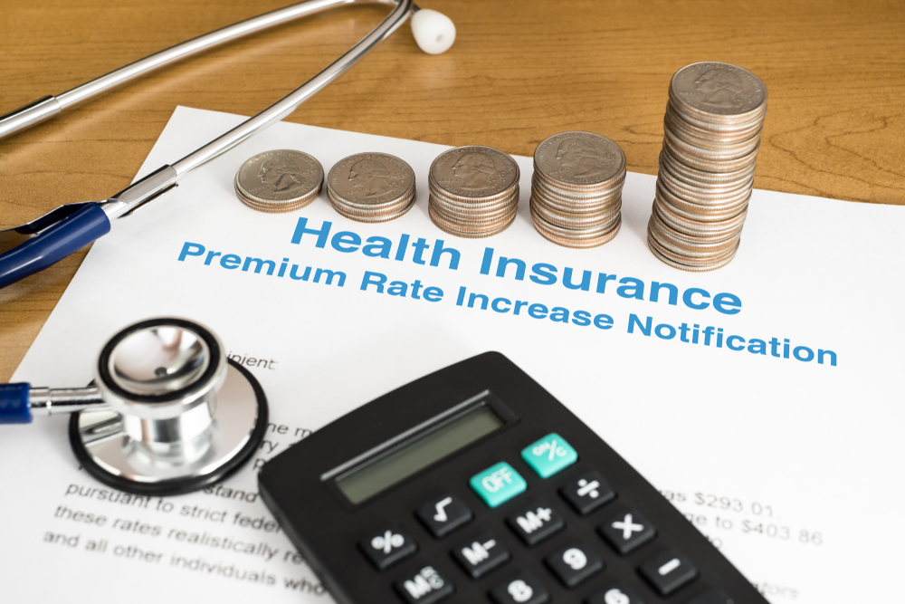 An insurance price increase notification surrounded by coins, calculator, and stethescope.